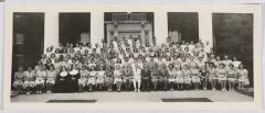 Group of men and women in front of building with white pillars