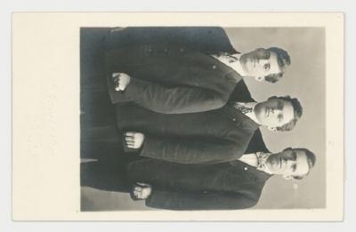 Three men posing for a photograph postcard